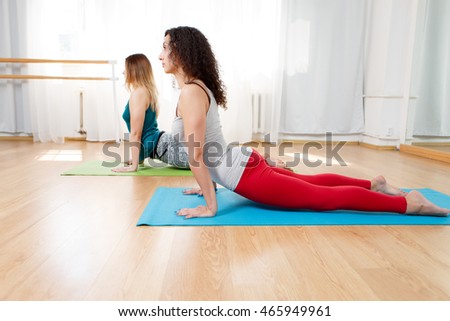 Portrait of flexible yogini doing asana bhujangasana in yoga studio