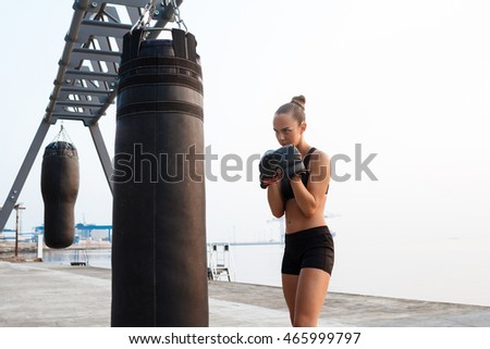 Young beautiful sportive girl training boxing at seaside.