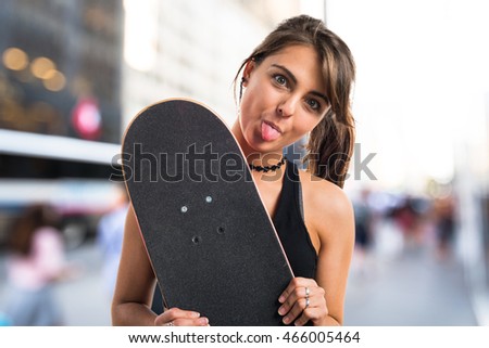 Young girl with skateboard on unfocused background