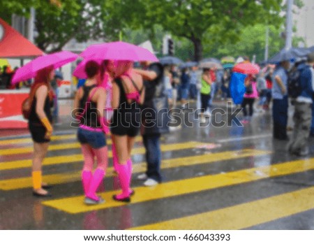 A blurred picture of teenagers in colorful cloths among crowded people in rainy day.