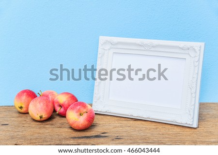 White photo frame and apples on the old wooden background