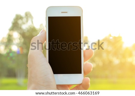 Hand holding smartphone with blank screen on nature background