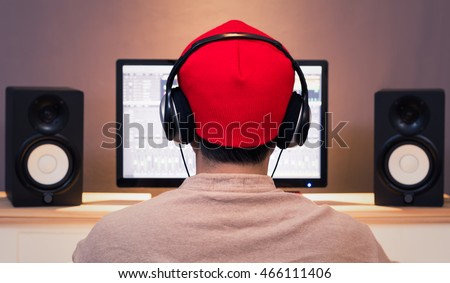 back of asian man listening music with professional audio equipment in home studio