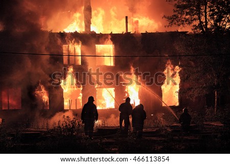 silhouettes of  firefighters on on burning house background