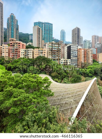 View on residential area of Hong Kong with high-rise apartment buildings rising over Hong Kong Park with Edward Youde Aviary dome of birds exibition