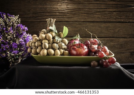 still life fruit include grape ,longan, dragon fruit, apple and dried flower on black cloth.  Adjustment  beautiful color image sepia style. 