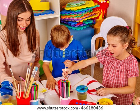 Children with teacher woman painting on paper at table in school. Painting school.