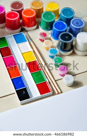 Artist painting with water colors, gouache, album and brushes on wooden table