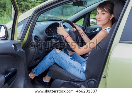 Young caucasian girl in drivers seat. Door open. Smile.