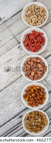 Super food tiger nuts, mulberry berries, cacao beans, goji berries, quinoa seeds, golden berry in white bowls over wooden background
