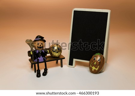 Halloween Pumpkin doll sit on the bench near blackboard