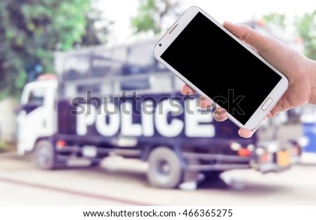 Man use mobile phone, blur image of police truck as background.