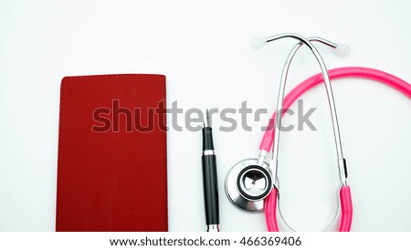 Conceptual of a medical photo with the diary and pen with pink stethoscope on a white background.