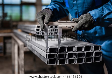 Factory worker measures the metal profile Royalty-Free Stock Photo #466436906