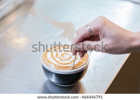 Barista creates a caramell picture in a cup of coffee latte