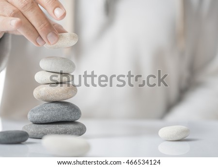 Horizontal image of a man stacking pebbles on a table with copyspace for text. Concept of personal development or self realization. Royalty-Free Stock Photo #466534124