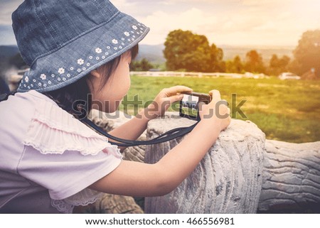 Side view of asian girl with camera at park . Children were photographed views. Child relaxing outdoors with bright sunlight at the daytime, travel on vacation. Vintage tone.