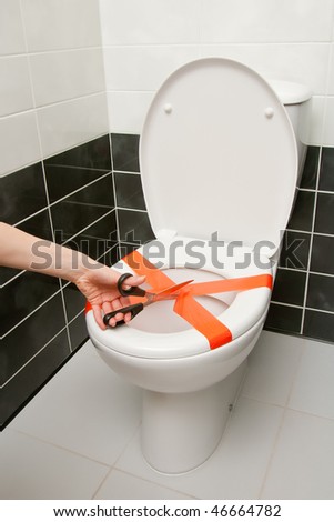 Scissors cutting the adhesive tape on the toilet