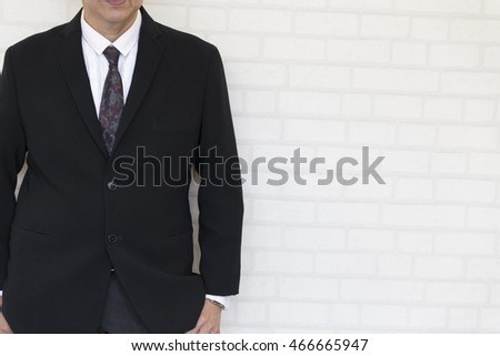 businessman hand in pocket standing beside white wall