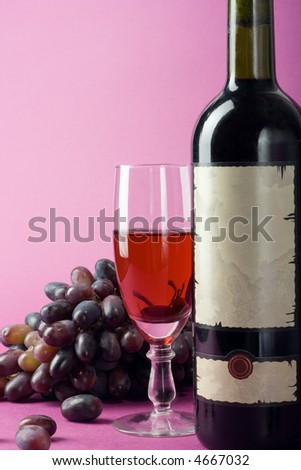 Bottle with the wine, the filled glass and a cluster of a grapes.