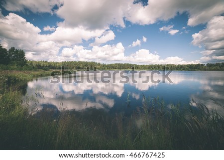 reflections in the lake water at sunrise with clouds and dramatic colors - vintage film effect