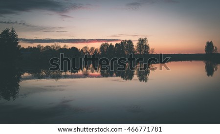 Beautiful dramatic sunset over the lake with clouds and reflections - vintage film effect