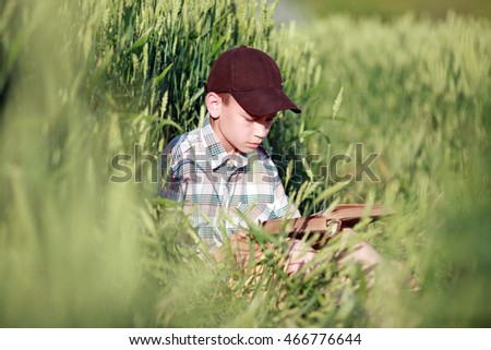 boy reads a book in a field of wheat
