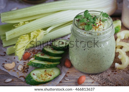 Fresh organic green smoothie with cucumber, parsley and celery on wooden background