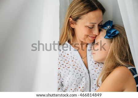 bright picture of hugging mother and daughter. Mom and teen girl. White