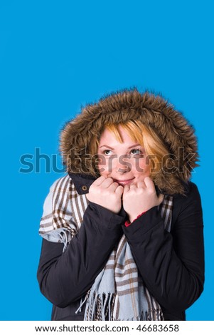 Daydreaming young woman in winter clothes in studio.