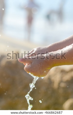 Happy child holding hands in water. Summer outdoors background