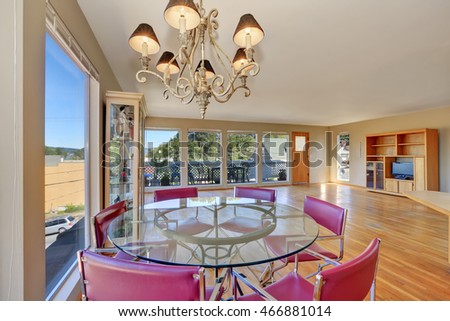 Dining area with round glass table and red chairs. Spacious empty living room with hardwood floor. Northwest, USA