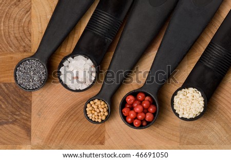 Five measuring spoons on a cutting board with various spices