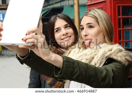 Portrait of two young girlfriends taking selfie with tablet on a trip together. Tourism concept. Outdoors.