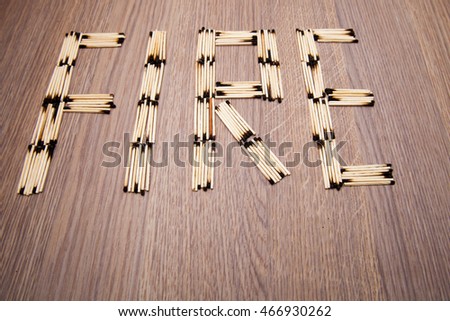 Laid word fire from burned wooden matches on a wooden background