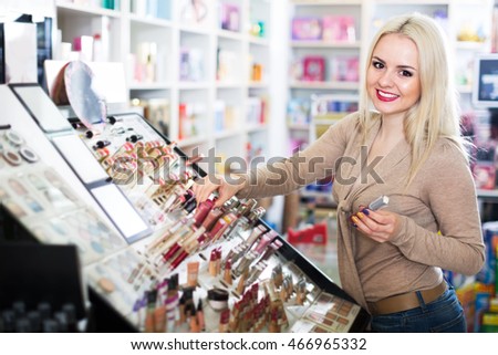Young positive blond woman choosing lip plumper on display Royalty-Free Stock Photo #466965332