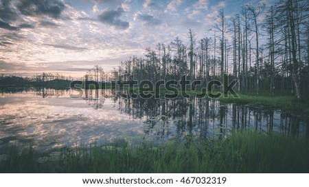 reflections in the lake water at sunrise with clouds and dramatic colors - vintage film effect