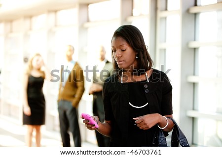 A business woman with a smart phone with colleagues in the background