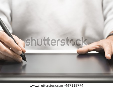 Close up of the hand of a graphic designer holding an electronic stylus. Background with free space for text, horizontal image 