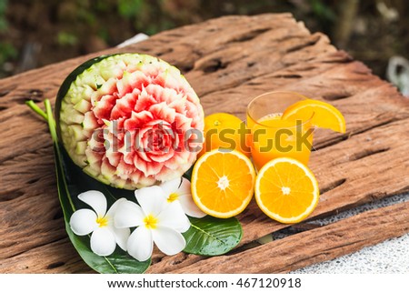 carved watermelon and orange juice with plumeria white flower on wooden table