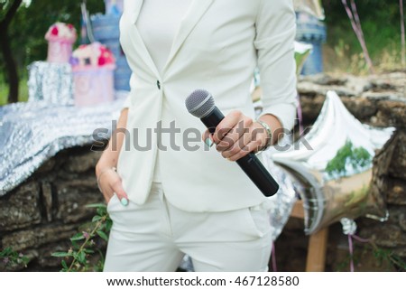 Hands of a woman with a microphone in the street at a children's party
