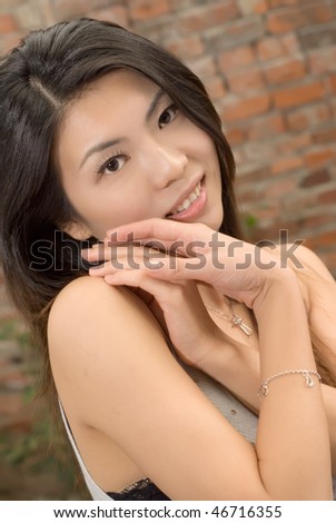 Charming woman in Asian portrait against old brick wall.