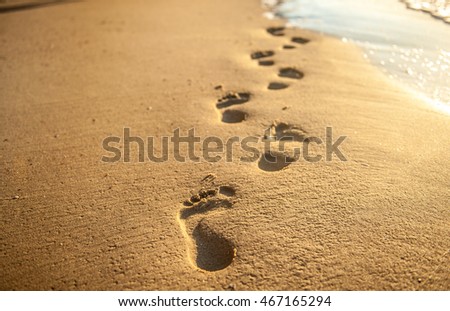 Footprints at sunset with golden sand. beach, wave and footsteps at sunset time Royalty-Free Stock Photo #467165294