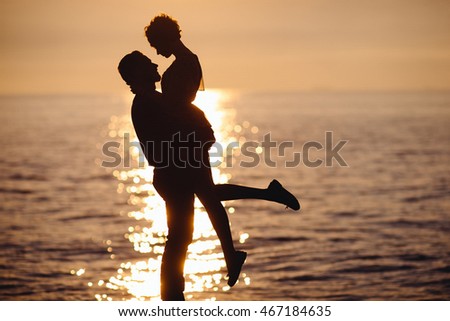 A picture in warm tones of a couple standing in the lights of evening sun