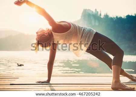 Beautiful woman practicing Yoga by the lake. Sunset. Toned image Royalty-Free Stock Photo #467205242