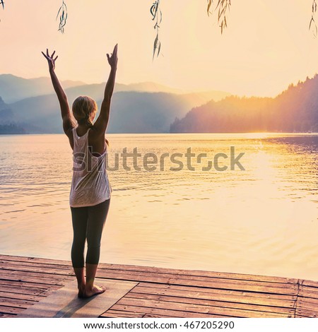 Beautiful woman practicing Yoga by the lake - Sun salutation series - Toned image Royalty-Free Stock Photo #467205290