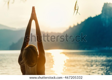 Beautiful woman practicing Yoga by the lake - Sun salutation series - Upward hands pose - Toned image Royalty-Free Stock Photo #467205332