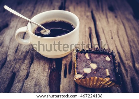 Piece of cake chocolate brownie and hot coffee on old wooden background. Shallow depth of field (dof), selective focus. High contrast and low key light picture style.
