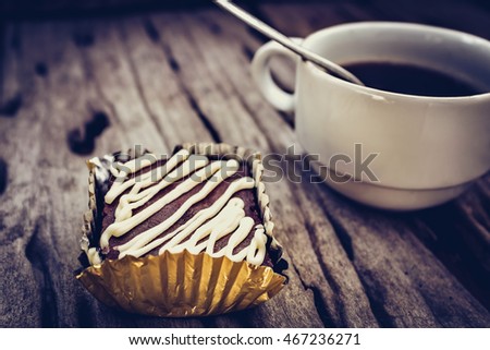 Piece of cake chocolate brownie and hot coffee on old wooden background. Shallow depth of field (dof), selective focus. High contrast and low key light picture style.