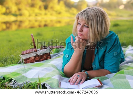 woman in park with book on the grass